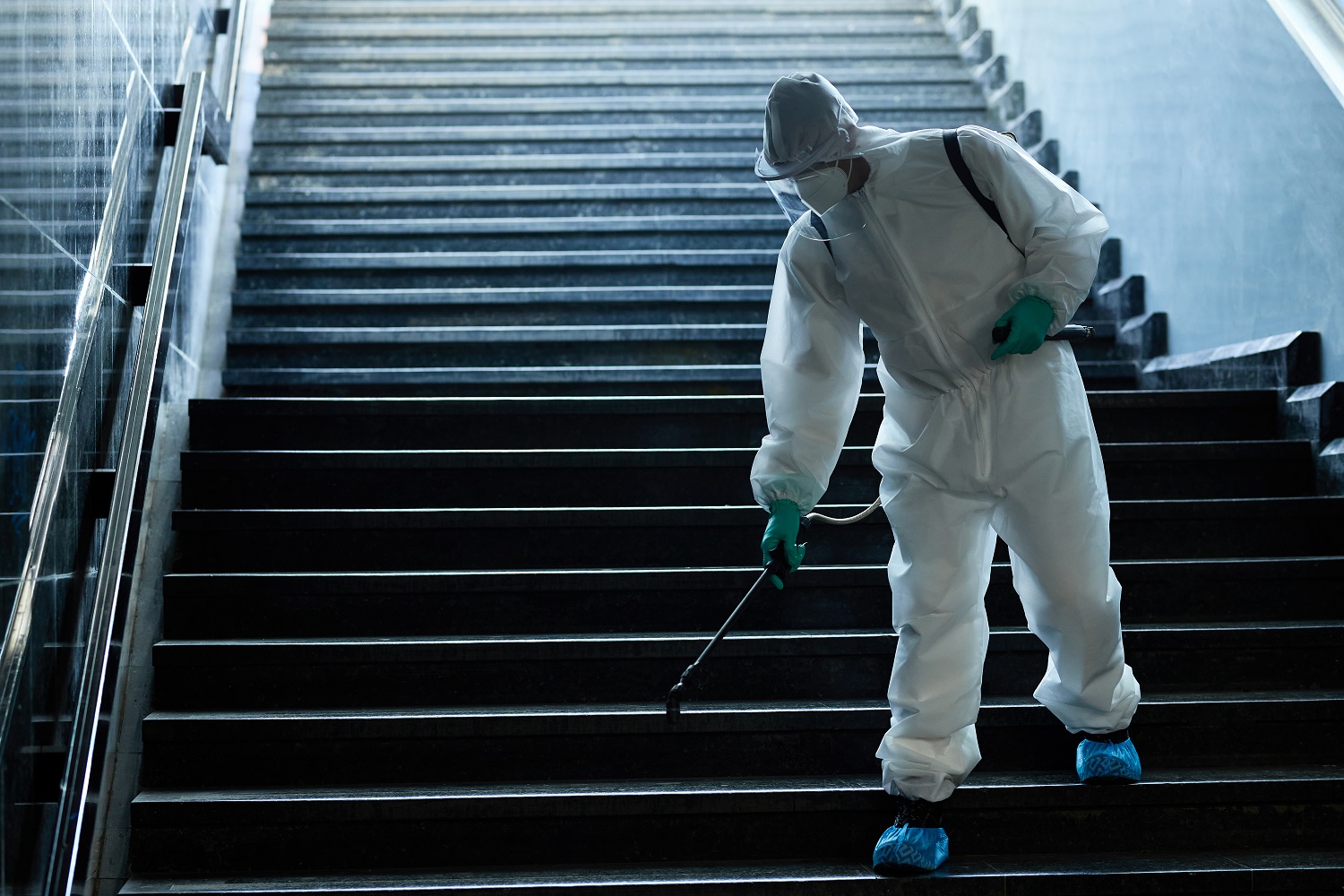 Disinfection worker spraying subway staircase due to COVID-19 pa